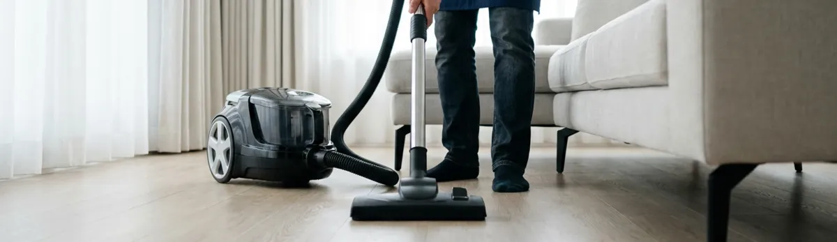 Professional house cleaner vacuuming a living room floor with a canister vacuum cleaner, Saint Petersburg, FL.